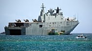 يمر قارب دورية تابع لشرطة بابوا غينيا الجديدة بجوار السفينة البحرية الأسترالية HMAS Adelaide أثناء رسوها قبالة سواحل APEC Haus، المكان الرئيسي لقمة أسبوع القادة الاقتصاديين 