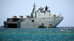 يمر قارب دورية تابع لشرطة بابوا غينيا الجديدة بجوار السفينة البحرية الأسترالية HMAS Adelaide أثناء رسوها قبالة سواحل APEC Haus، المكان الرئيسي لقمة أسبوع القادة الاقتصاديين 