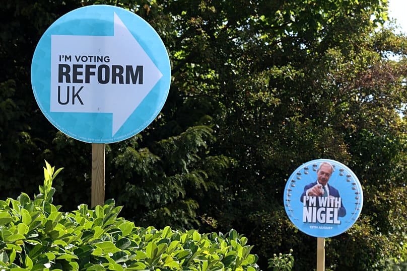 Election signs for Britain's Reform UK party leader Nigel Farage are seen in gardens in Thorpe-Le-Soken, 13 August, 2026 