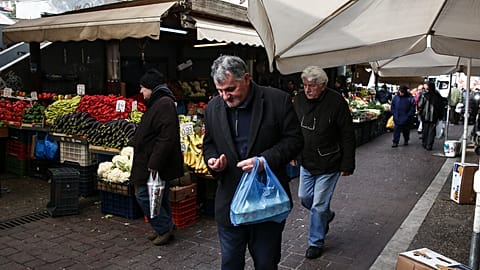 A man counts his cash at a central food market in Athens, Saturday 11 February 2017