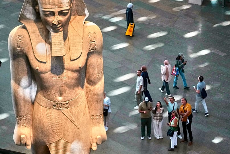 Visitors beside a statue of Ramses II at the Grand Egyptian Museum in Giza, Egypt, on 4 November 2025.