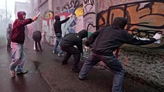 Protesters spray paint on a wall during a demonstration against ICE organized by students at the 2026 Winter Olympics, in Milan, Italy, Friday, Feb. 6, 2026