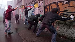 Protesters spray paint on a wall during a demonstration against ICE organized by students at the 2026 Winter Olympics, in Milan, Italy, Friday, Feb. 6, 2026