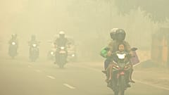 Motorists ride on a road amid haze from forest fires in Palangkaraya, Central Kalimantan