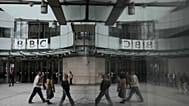 Pedestrians reflected outside BBC Broadcasting House in London, 11 November 2025.