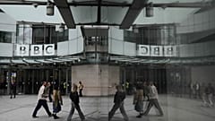 Pedestrians reflected outside BBC Broadcasting House in London, 11 November 2025.