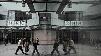 Pedestrians reflected outside BBC Broadcasting House in London, 11 November 2025.