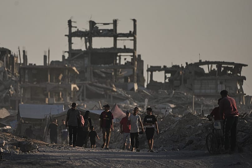 فلسطينيون يسيرون وسط أنقاض مبانٍ دمرتها الغارات الإسرائيلية في مدينة غزة، 17 أغسطس 2026.