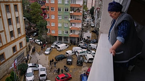 Vecinos recorren entre vehículos volcados y escombros esparcidos tras las inundaciones provocadas por las fuertes lluvias.