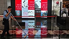 A worker mops the floor near an electronic screen displaying stock prices at the Indonesia Stock Exchange in Jakarta, Friday, 16 Oct. 2026.