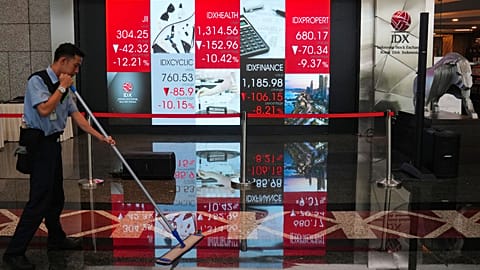 A worker mops the floor near an electronic screen displaying stock prices at the Indonesia Stock Exchange in Jakarta, Friday, 16 Oct. 2026.