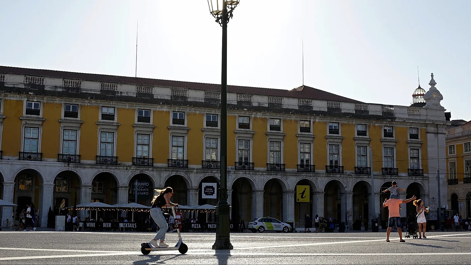 A girl rides an electric scooter across Praça do Comércio in Lisbon on Thursday, 12 August 2021