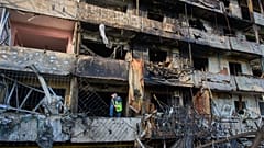 A municipal worker examines a damaged apartment building after Russia's night missile attack in Kyiv, 14 October, 2026