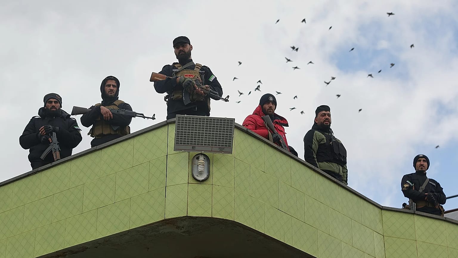 عناصر من أجهزة أمن الحكومة السورية يقفون للحراسة أثناء وصول سجناء بعد إطلاق سراحهم في عملية تبادل للأسرى بين القوات الحكومية السورية ومسلحين دروز في محافظة السويداء بسوريا
