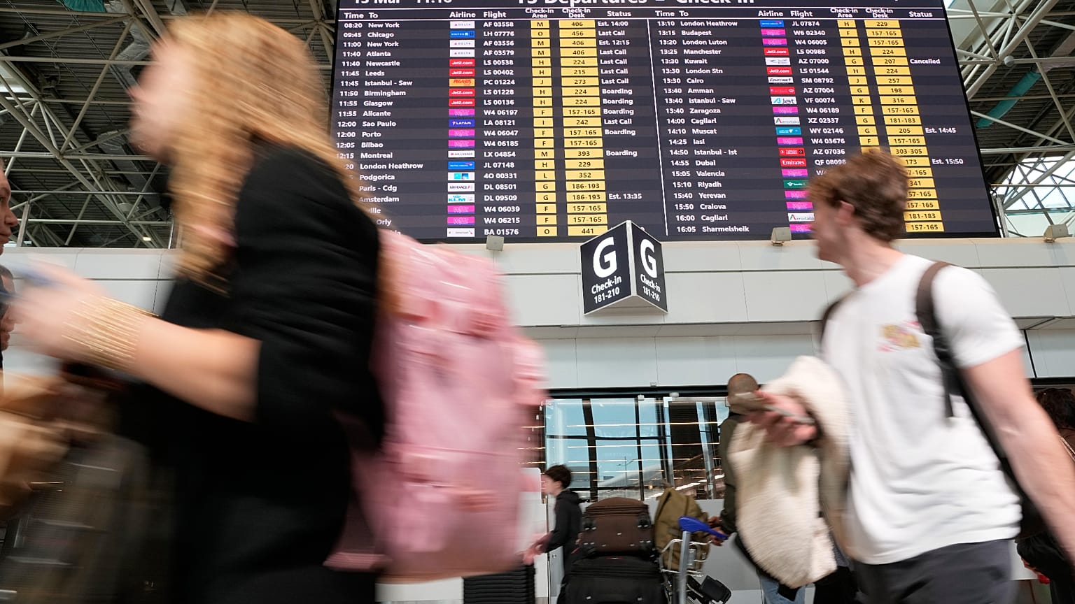 Pasajeros pasan junto a un panel de información de vuelos en el aeropuerto internacional Leonardo Da Vinci de Roma, en Fiumicino