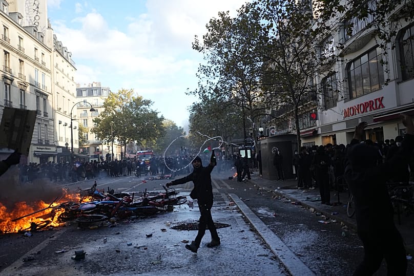 Protesters stand in front of burning bicycles during a demonstration against rising living costs, joining students' grievances, in Paris, Saturday, Oct. 17, 2026.