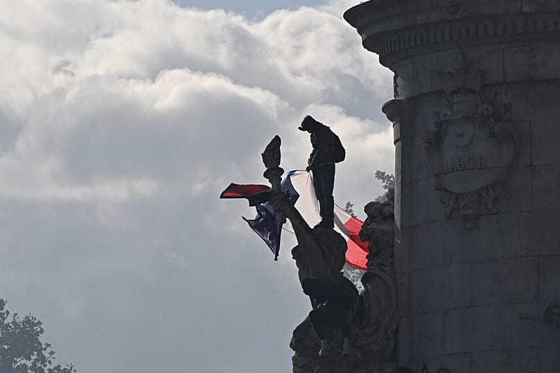 A protester stands with a French flag at the Republique plaza during a protest against rising living costs, in solidarity with students, Lyon, France, Saturday, Oct. 17, 2026