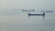People wade in the water as cargo ships are anchored in the Strait of Hormuz off Bandar Abbas, Iran, early Monday, Sept. 28, 2026.