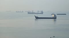 People wade in the water as cargo ships are anchored in the Strait of Hormuz off Bandar Abbas, Iran, early Monday, Sept. 28, 2026.