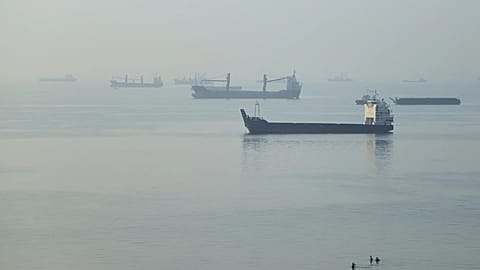 People wade in the water as cargo ships are anchored in the Strait of Hormuz off Bandar Abbas, Iran, early Monday, Sept. 28, 2026.