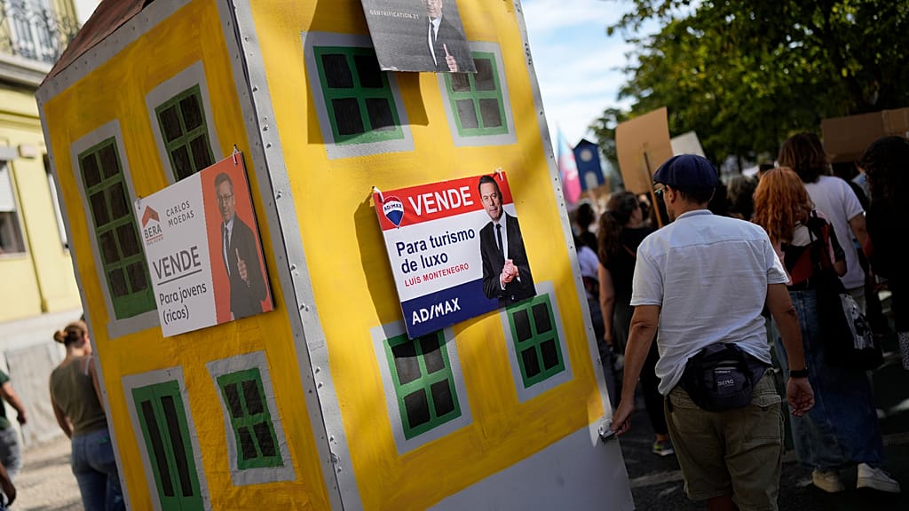 FILE (28.09.2024) Activists push a model building with posters styled like property ads, showing photos of the prime minister.