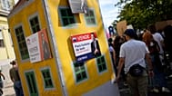 ARCHIVIO (28.09.2024) Attivisti spingono un plastico di edificio con cartelloni simili agli annunci immobiliari, con fotografie del primo ministro