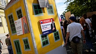 ARQUIVO (28.09.2024) Os ativistas empurram uma maquete de edifício com cartazes ao estilo dos anunciados no setor imobiliário, com fotografias do primeiro-ministro