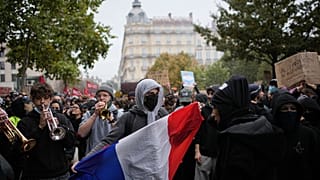 Egy tüntető francia zászlót tart az emelkedő megélhetési költségek ellen, a diákok tiltakozásához csatlakozva tartott lyoni demonstráción 2026. október 17-én.