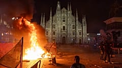 Un incendio arde tras los enfrentamientos entre la Policía y los manifestantes de 'Italia in Piazza' frente a la catedral de Milán (Italia), el 17 de octubre de 2026. 