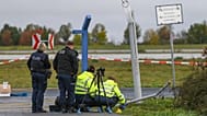 Police officers inspect the site of a damaged fence section at the entrance to the Leipzig/Halle airport grounds, 18 October, 2026
