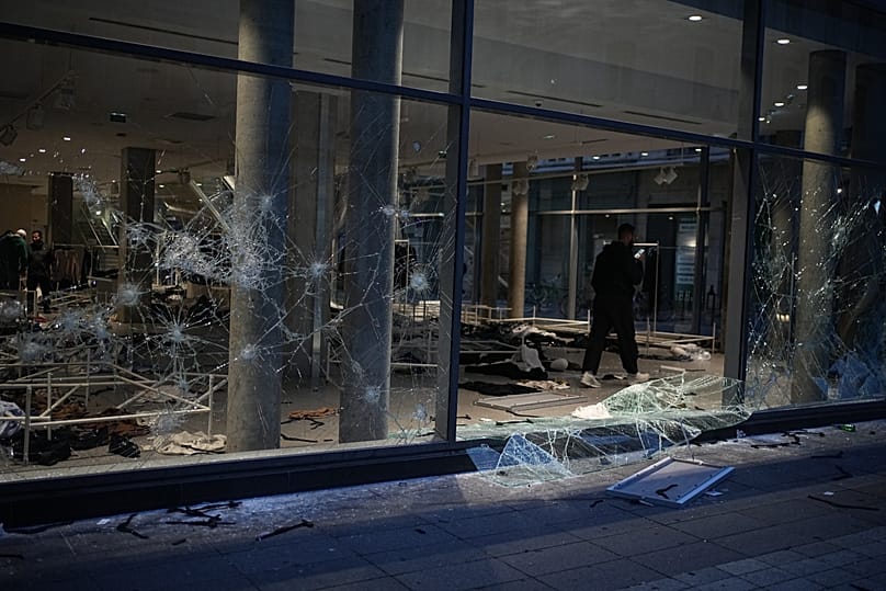 Ein Mann fotografiert einen geplünderten Laden nach einer Demonstration gegen steigende Lebenshaltungskosten, bei der sich die Protestierenden den Forderungen von Studierenden anschließen, in Lyon, Frankreich, Samstag, 17. Oktober 2026.