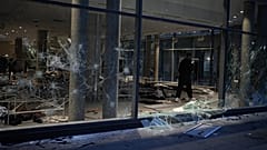 A man takes photos of a looted store after a demonstration against rising living costs, joining students' grievances, in Lyon, France, Saturday, Oct. 17, 2026