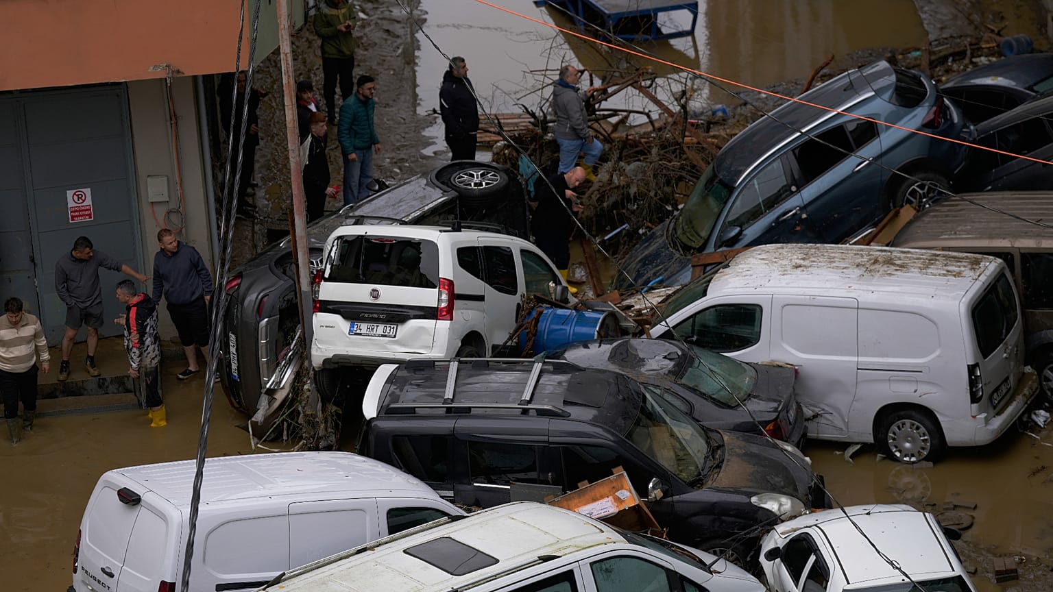 İstanbul'da şiddetli yağışların yol açtığı sellerin ardından bölge sakinleri, devrilmiş araçların ve etrafa saçılmış enkazın arasında yürüyor, 15 Ekim 2026.