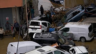 İstanbul'da şiddetli yağışların yol açtığı sellerin ardından bölge sakinleri, devrilmiş araçların ve etrafa saçılmış enkazın arasında yürüyor, 15 Ekim 2026.