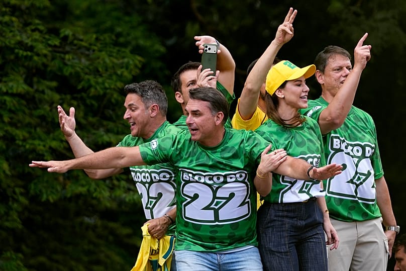 O candidato presidencial da oposição, o senador Flavio Bolsonaro, à frente, acena aos apoiantes durante um comício de campanha em São Paulo,