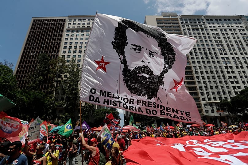 Os apoiantes agitam uma bandeira gigante com a imagem do presidente brasileiro Luiz Inácio Lula da Silva, que se candidata à reeleição,