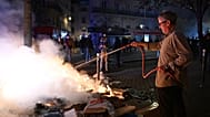 A man tries to extinguish a fire during clashes between protesters and police in Paris, Sunday, Oct. 18, 2026