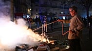 Egy férfi megpróbál eloltani egy tüzet a tüntetők és a rendőrség összecsapásai során Párizsban, 2026. október 18-án