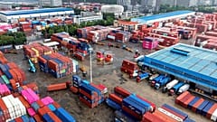 Contentores são carregados e descarregados em camiões num terminal em Qingdao, na província de Shandong, no leste da China, em 28 de agosto de 2026. (Chinatopix via AP)