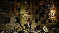 Rescue workers walk in front of a residential building damaged by a Russian airstrike in Zaporizhzhia, 17 October, 2026