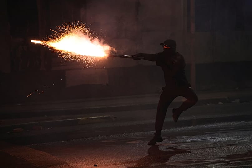 Manifestante encapuzado aponta foguetes à polícia durante confrontos numa manifestação antigovernamental em Tirana, 18 de outubro de 2026