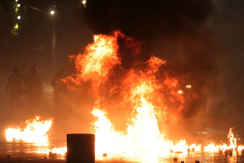 Manifestantes lançam engenhos incendiários contra a polícia durante confrontos numa manifestação antigovernamental em Tirana, 18 de outubro de 2026