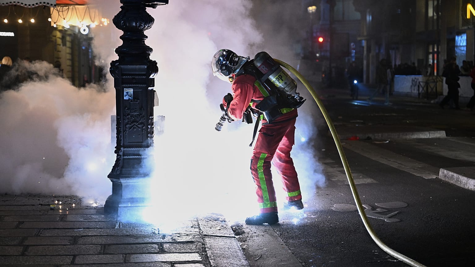 Un bombero apaga un incendio durante los enfrentamientos entre manifestantes y la Policía en París, el domingo 18 de octubre de 2026. 
