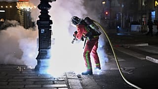 Un bombero apaga un incendio durante los enfrentamientos entre manifestantes y la Policía en París, el domingo 18 de octubre de 2026. 