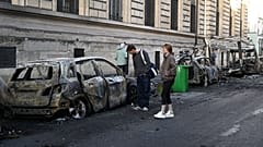 ARQUIVO. Pessoas observam um carro carbonizado perto da Place de la République, no dia seguinte a protestos contra o aumento do custo de vida em Paris, 18 out. 2026