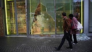 Przechodnie oglądają zniszczenia po zamieszkach na obrzeżach protestów, Paryż, poniedziałek 19 października 2026.