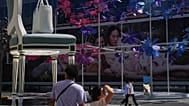File - Shoppers walk by a giant chair and a handbag on display at a luxury outdoor shopping mall decorated with flower shaped fans in Beijing, Thursday, 3 Sept. 2026. 