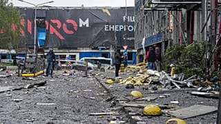 Az emberek egy megrongálódott irodaközpontot néznek az orosz rakétatámadás után Kijev központjában, Ukrajnában, 2026. október 19-én, hétfőn.