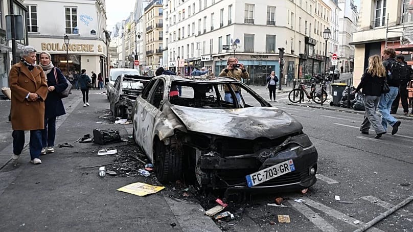 People look at charred cars the day after a demonstration against rising living costs and in solidarity with students' grievances, in Paris, Sunday, Oct. 18, 2026. 