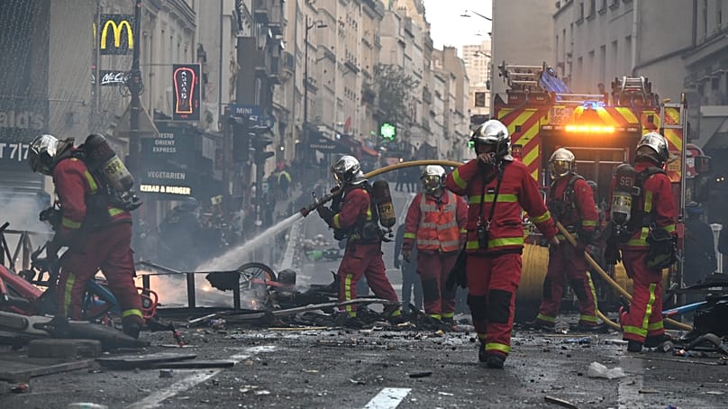 Des pompiers éteignent un incendie survenu à la suite d'une manifestation à Paris, le 17 octobre 2026.